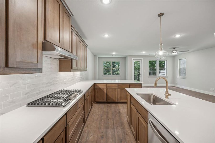 Kitchen with decorative light fixtures, appliances with stainless steel finishes, sink, dark wood-type flooring, and ceiling fan