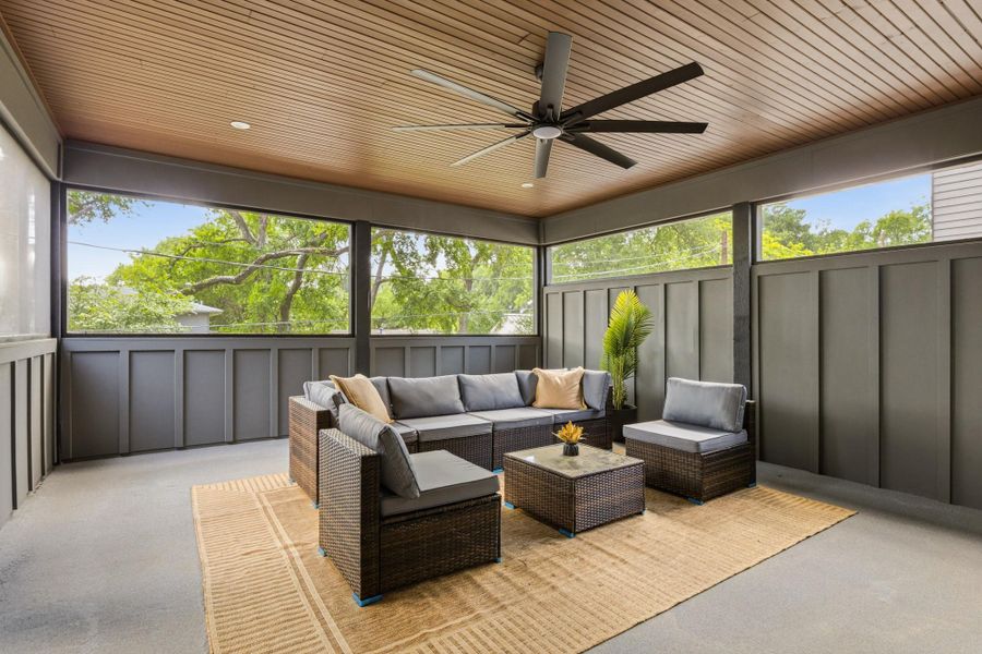 Screened porch featuring a wood-panel ceiling, concrete flooring, and a ceiling fan