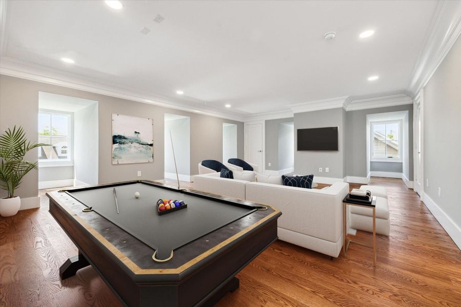 This 3rd floor flex/media/game room is a spacious, well-lit living area features elegant hardwood floors, a cozy seating arrangement, and a stylish pool table. Large windows bring in natural light, while modern decor and a minimalist design create a welcoming atmosphere.  Use your own imagination for what your family would like here!  This photo has been virtually staged.