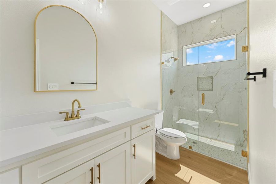 Bathroom with a marble finish shower, vanity, and light wood-style flooring