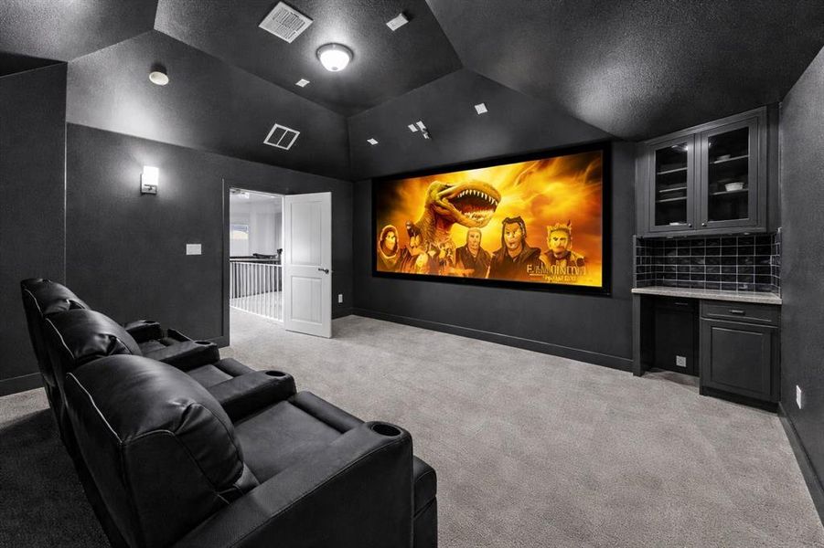 Dedicated media room featuring a large projection screen, dark wall finishes, and recessed ceiling lighting Dedicated media room featuring a large projection screen, dark wall finishes, and recessed ceiling lighting
