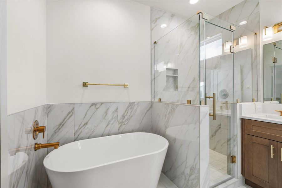 Freestanding soaking tub, marble-look tile, and gold fixtures throughout Freestanding soaking tub, marble-look tile, and gold fixtures throughout