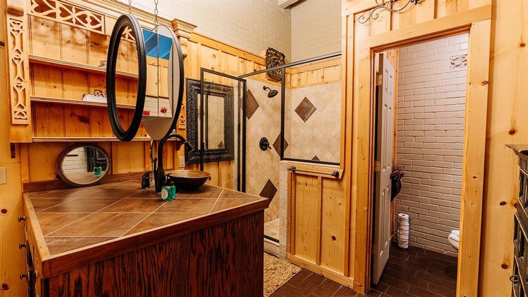 Bathroom with wood tiled floors, vanity, and wood walls