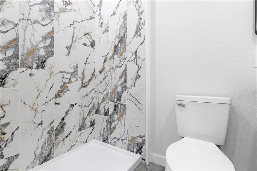 Bathroom featuring tiled shower and toilet