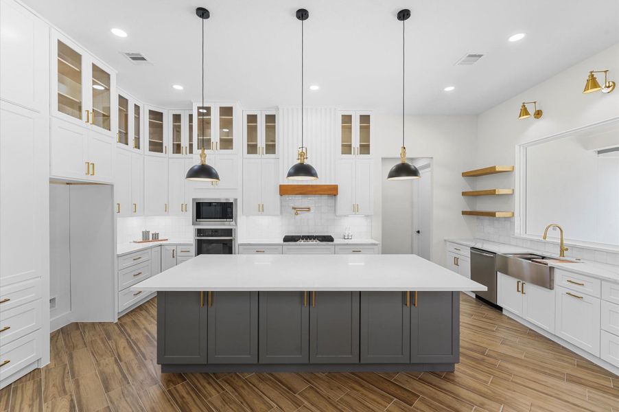 Chef’s dream kitchen featuring custom cabinetry, oversized island, quartz counters, modern fixtures, and abundant windows that overlook the backyard. Chef’s dream kitchen featuring custom cabinetry, oversized island, quartz counters, modern fixtures, and abundant windows that overlook the backyard.