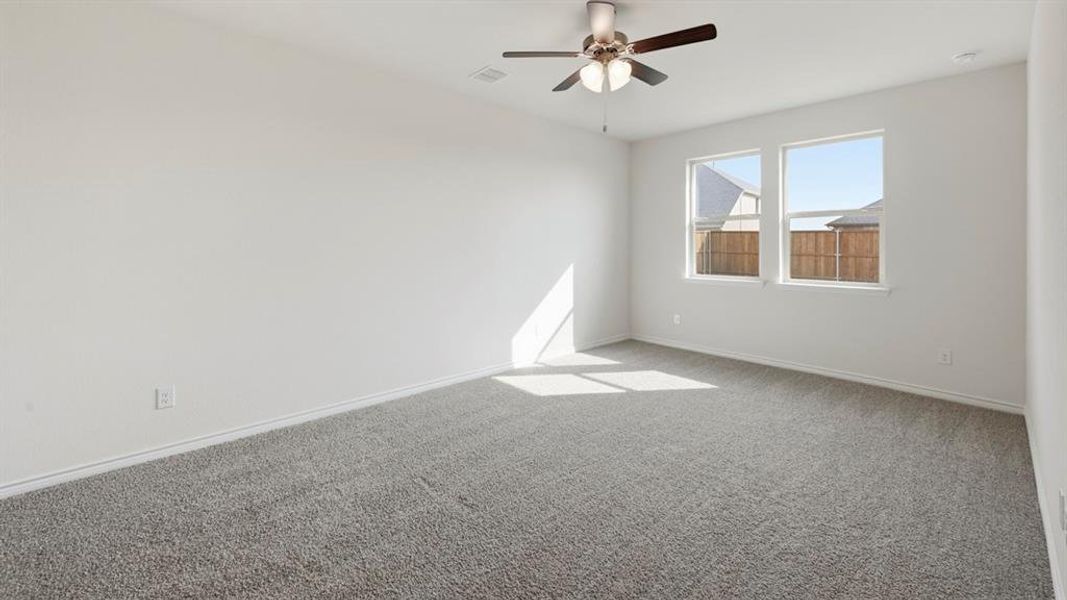 Carpeted interior space featuring white walls, two windows, a ceiling fan with integrated lighting, and white baseboards Carpeted interior space featuring white walls, two windows, a ceiling fan with integrated lighting, and white baseboards