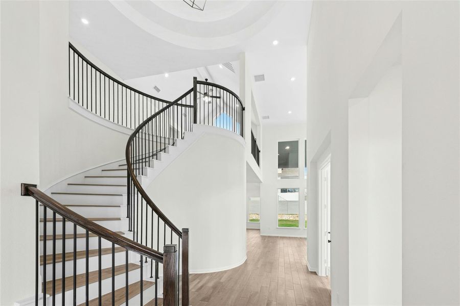 Stairway featuring a towering ceiling, wood finished floors, and recessed lighting Stairway featuring a towering ceiling, wood finished floors, and recessed lighting