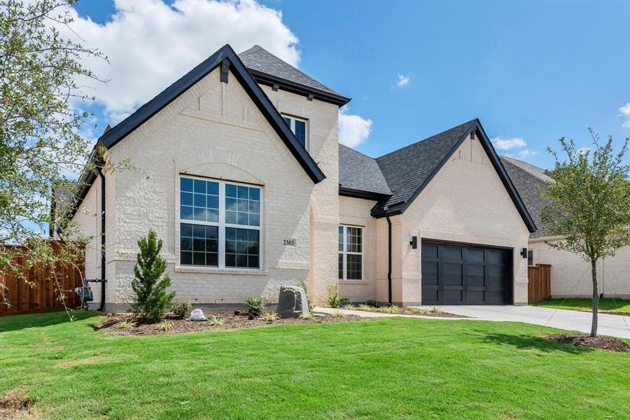 French country style house featuring a garage and a front yard