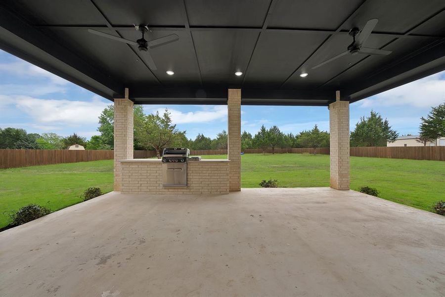The property features an expansive covered patio with a concrete surface, equipped with ceiling fans and recessed lighting