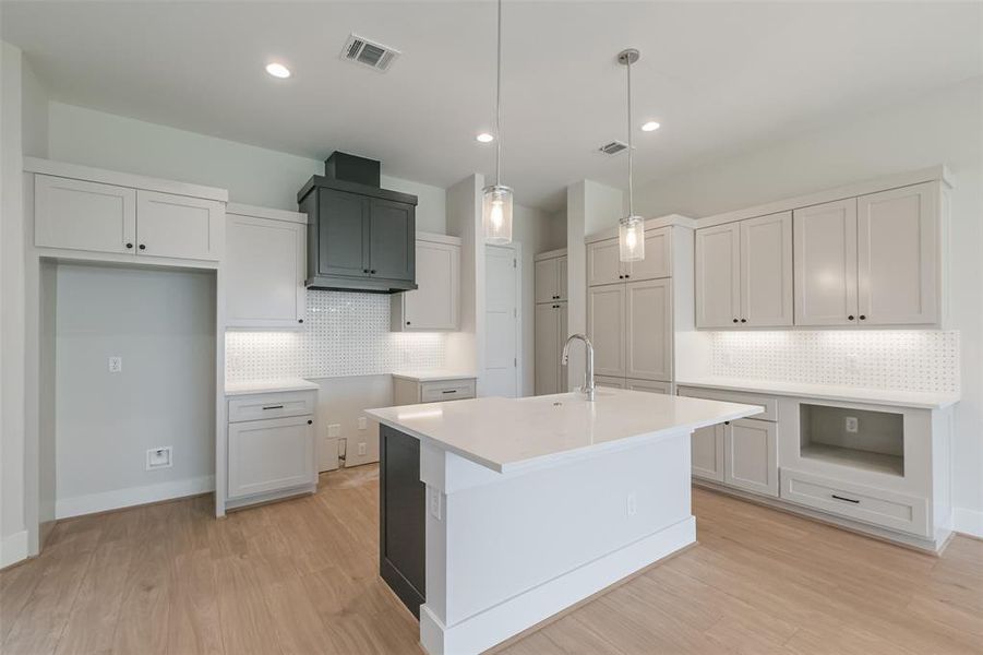 The chef's kitchen features a large island with breakfast bar, custom cabinetry and designer finishes.