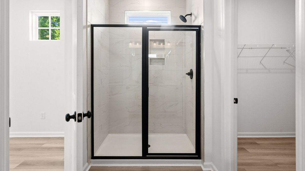 Step into a tiled walk-in shower framed by sleek glass doors