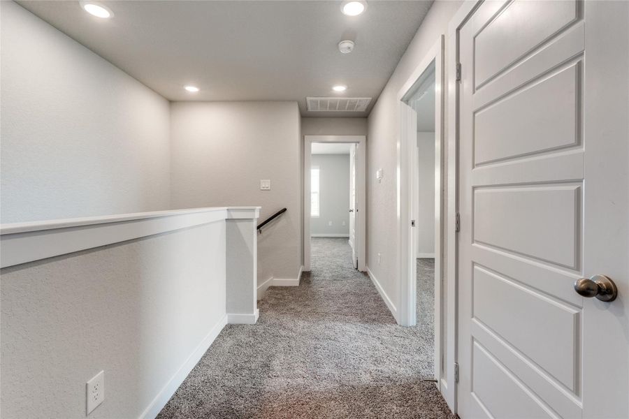 Hall featuring light carpet, recessed lighting, and an upstairs landing Hall featuring light carpet, recessed lighting, and an upstairs landing