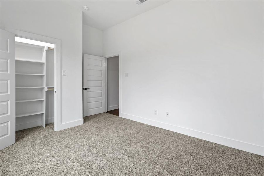 Unfurnished bedroom with a walk in closet, carpet floors, and a closet