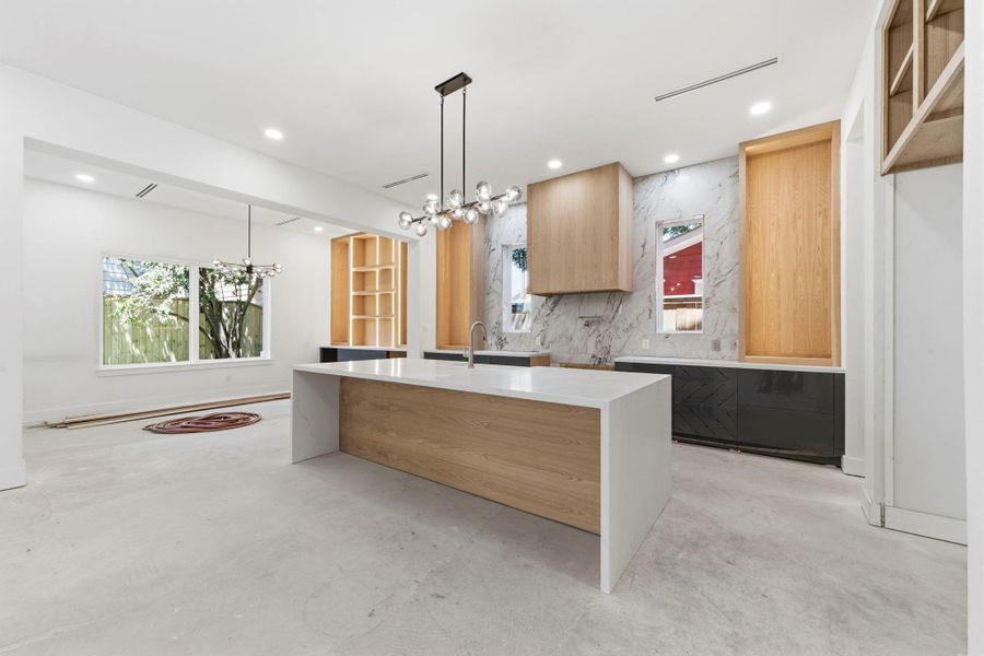 Another view showcasing the flow of the first floor living area, including the center island, vent hood, and custom cabinetry finishes. Another view showcasing the flow of the first floor living area, including the center island, vent hood, and custom cabinetry finishes.