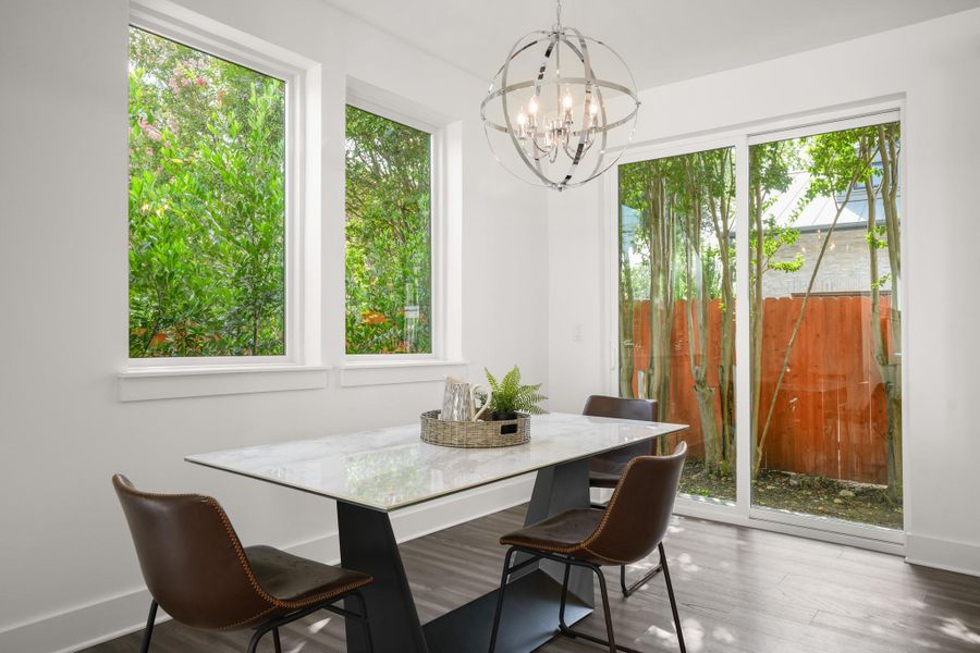 A well-lit dining area offers a seamless connection to the outdoors through large windows and a sliding glass door. A well-lit dining area offers a seamless connection to the outdoors through large windows and a sliding glass door.