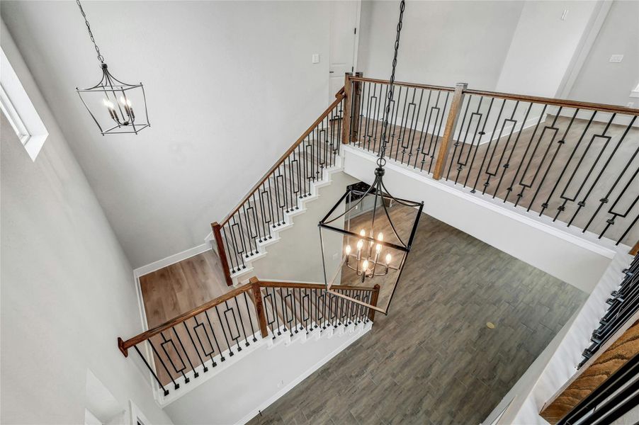 Stairway with a high ceiling, wood finished floors, and an inviting chandelier