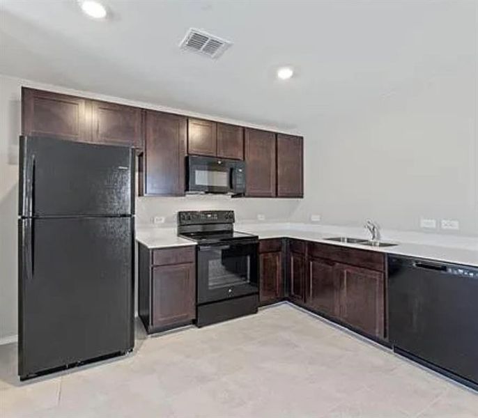 Kitchen with dark brown cabinets, black appliances, light countertops, and recessed lighting
