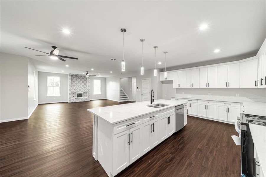 Kitchen with white cabinetry, dark wood finished floors, a kitchen island with sink, and light stone countertops
