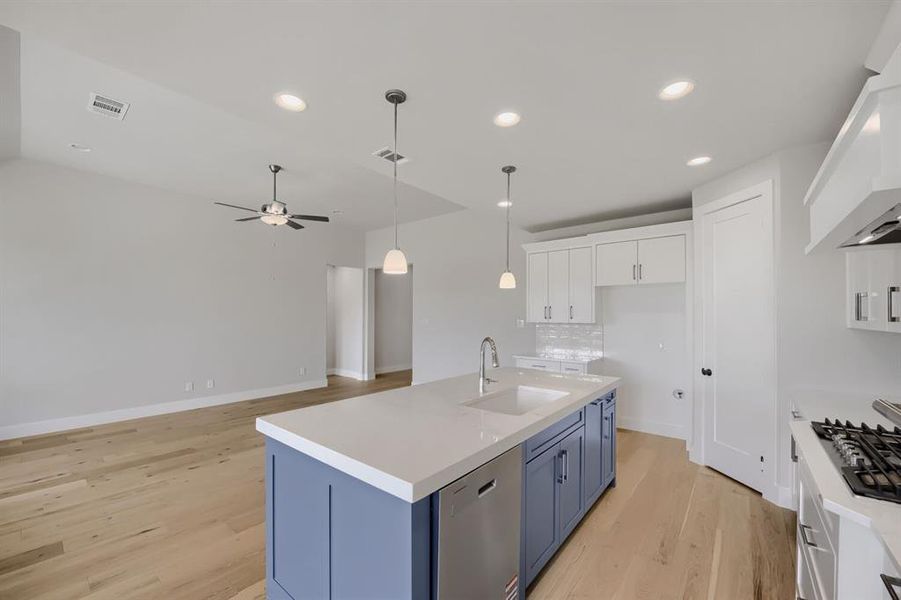 Kitchen island with a white countertop and blue cabinetry, featuring an undermount sink and a stainless steel faucet