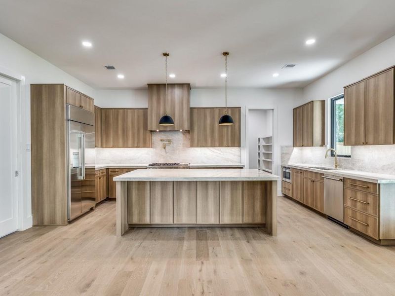 Kitchen with light wood-type flooring, pendant lighting, a large island, and stainless steel appliances