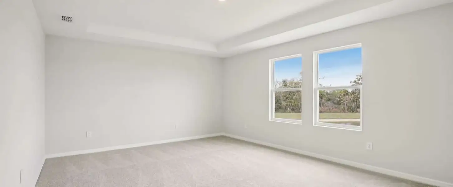 Primary bedroom located off the back of the home with two large windows and a tray ceiling - Representative images and renderings are for illustrative purposes. Actual structural options and design finishes of home may vary.
