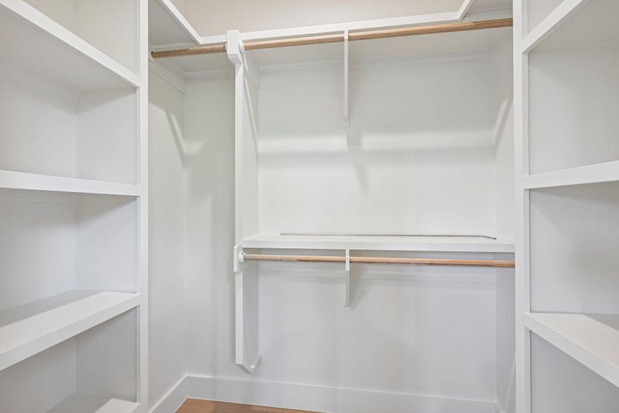 Ample shelving and hanging space defines this meticulously organized primary bedroom walk-in closet. Ample shelving and hanging space defines this meticulously organized primary bedroom walk-in closet.