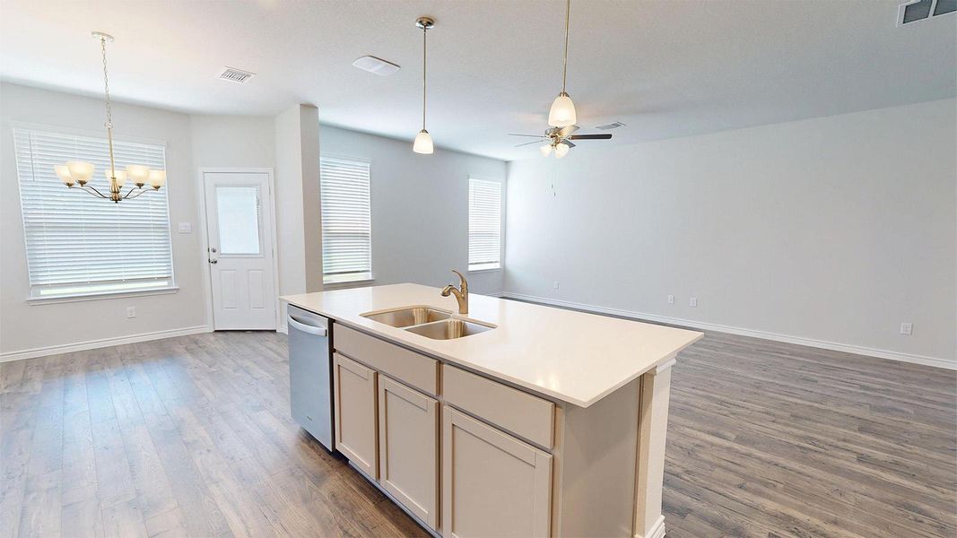The property features an open-concept living area with wood-style flooring, a kitchen island with a double sink, and a ceiling fan