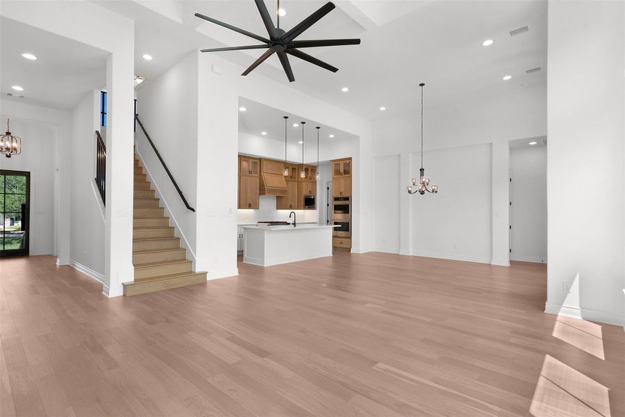 An open-concept interior offers seamless flow between living, kitchen, and dining spaces, complemented by gleaming hardwood floors and an elegant staircase.