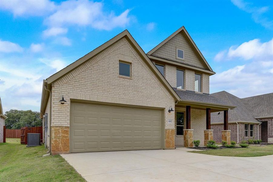 View of front of home featuring a garage, a front yard, and central air condition unit