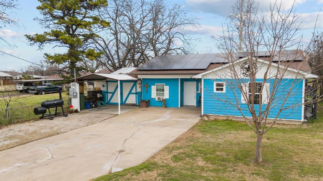 View of front of property featuring solar panels and a front yard