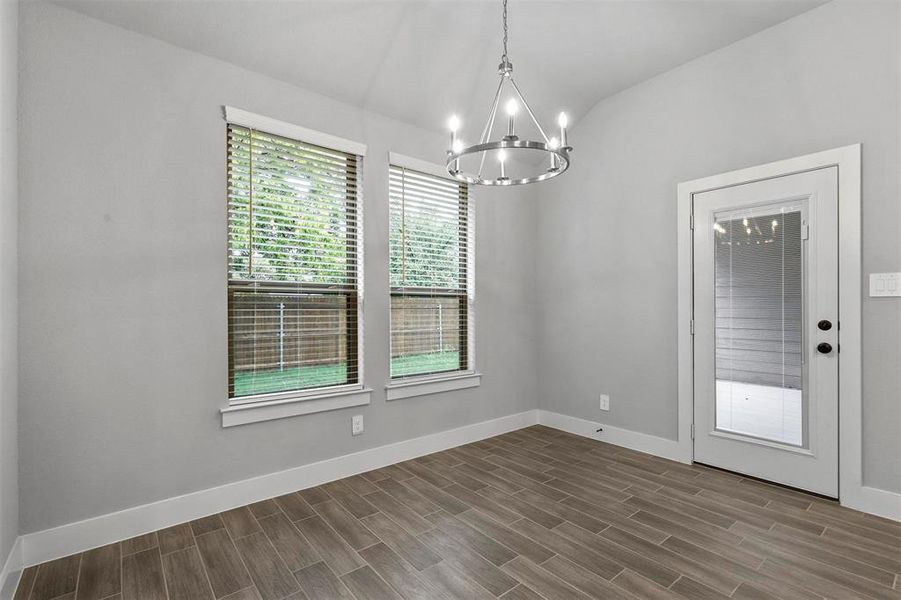 Unfurnished dining area with wood-type flooring, a chandelier, and vaulted ceiling