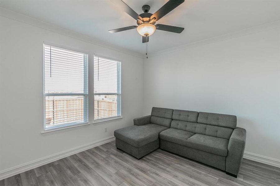 Living room with hardwood / wood-style floors, ceiling fan, and ornamental molding