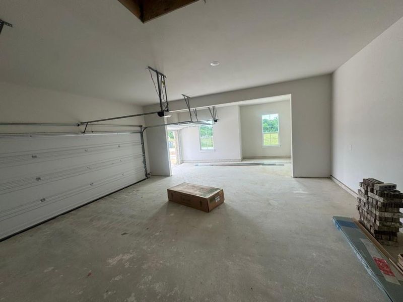 Spacious garage featuring a large overhead door, concrete flooring, and bare walls Spacious garage featuring a large overhead door, concrete flooring, and bare walls