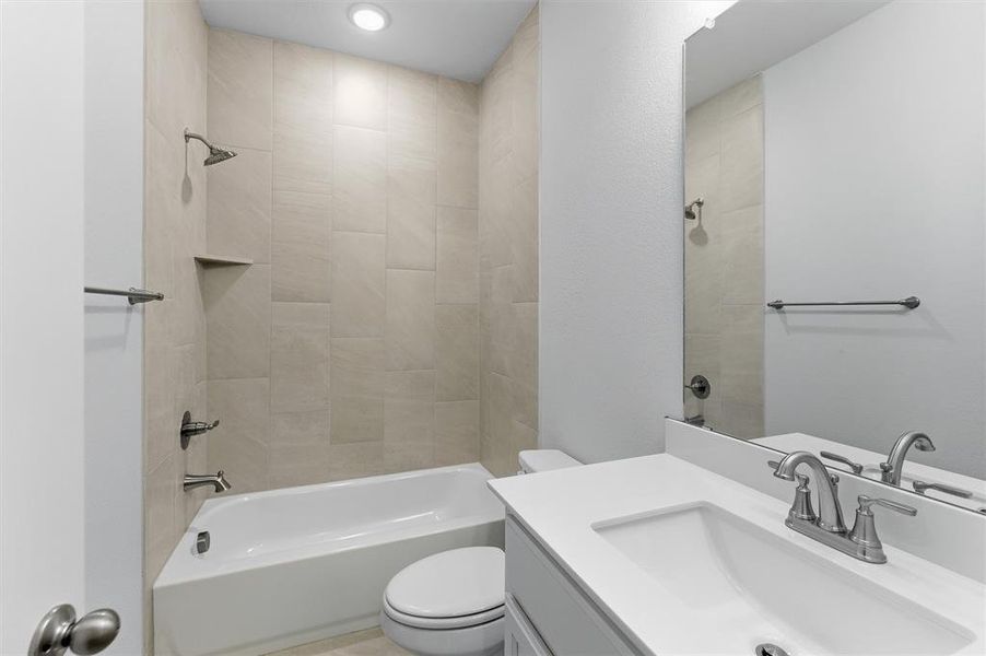 Full bathroom featuring a tub-shower combination with tiled surround, an integrated shower niche, and a vanity with a white countertop