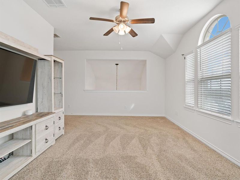 Unfurnished living room featuring ceiling fan, lofted ceiling, and light carpet