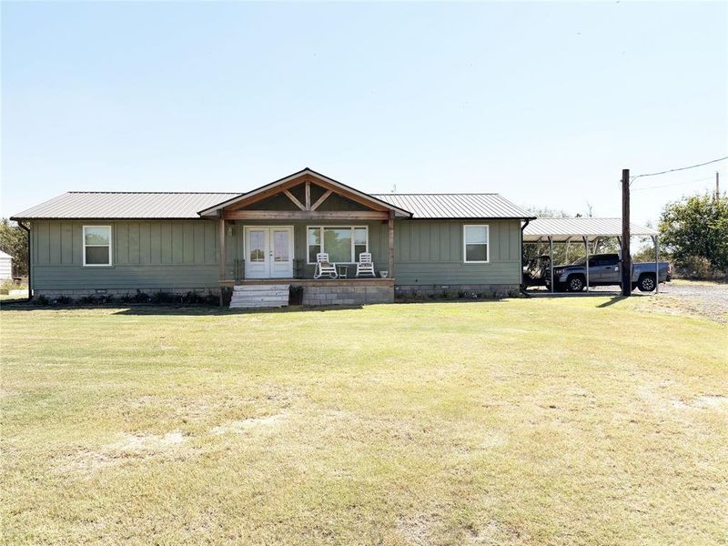 Front of house with a metal roof, a front lawn, and covered porch Front of house with a metal roof, a front lawn, and covered porch