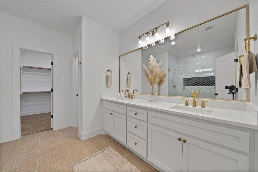 Full bathroom with a shower stall, double vanity, a spacious closet.