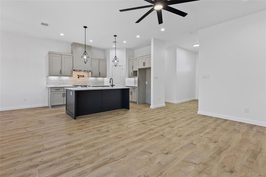 Kitchen with visible vents, gray cabinetry, a sink, open floor plan, and light countertops