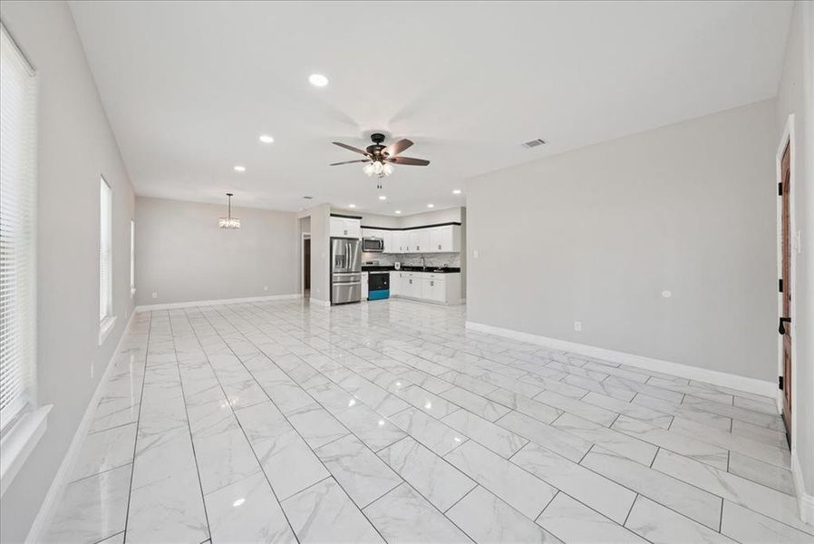 Unfurnished living room featuring recessed lighting, a chandelier, light marble finish floors, and ceiling fan