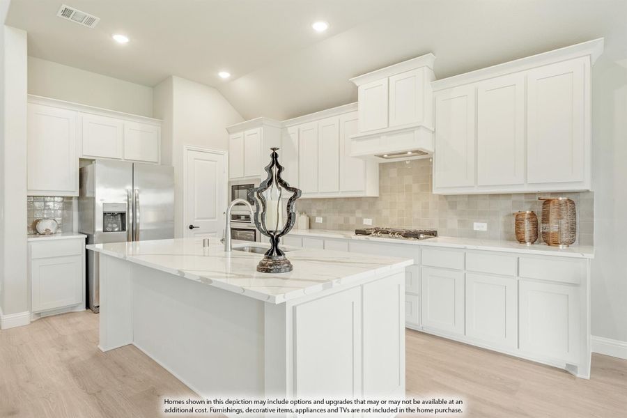 Kitchen with white cabinets, marble island, tile backsplash, and stainless steel appliances on light wood floors Kitchen with white cabinets, marble island, tile backsplash, and stainless steel appliances on light wood floors