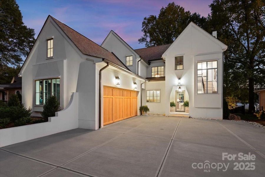 Double concrete poured driveway with side load garage featuring a custom wood door, High-mount motors, and epoxy floors. Double concrete poured driveway with side load garage featuring a custom wood door, High-mount motors, and epoxy floors.