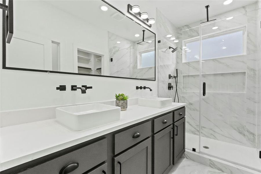 Full bathroom with double vanity, a marble finish shower, recessed lighting, light marble finish floors, and a spacious closet