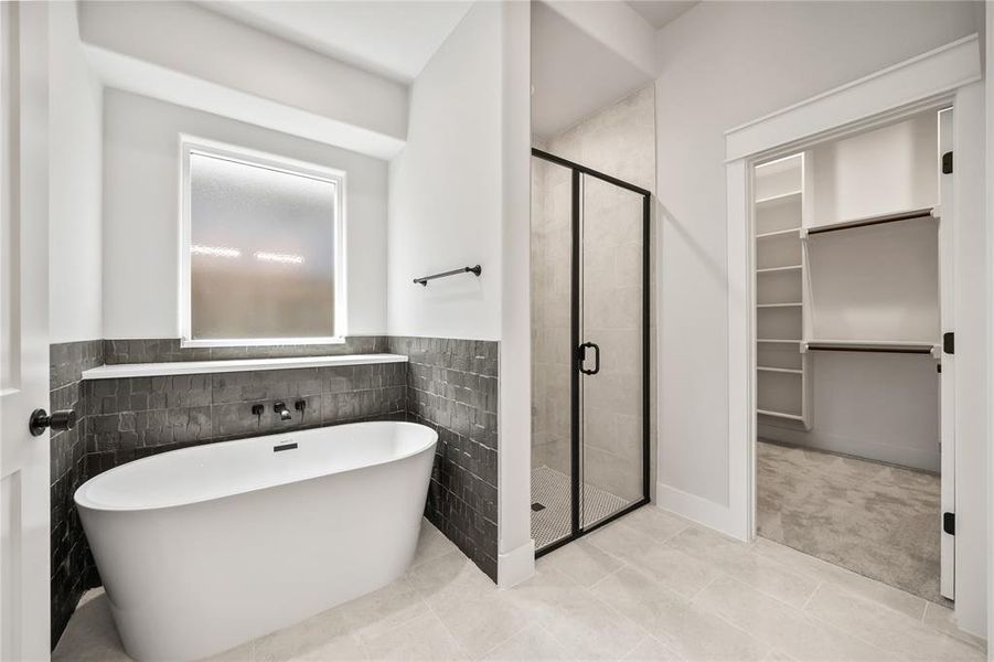 Bathroom featuring a freestanding soaking tub with matte black fixtures, a walk-in shower with a black-framed glass enclosure, and light-toned tile flooring