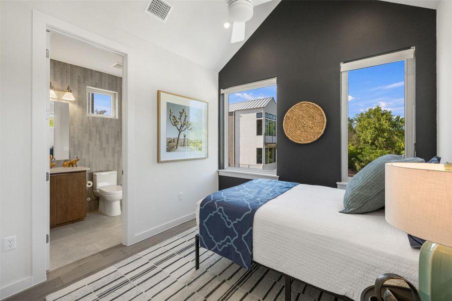 Bedroom featuring vaulted ceiling, light wood-style flooring, and ensuite bathroom