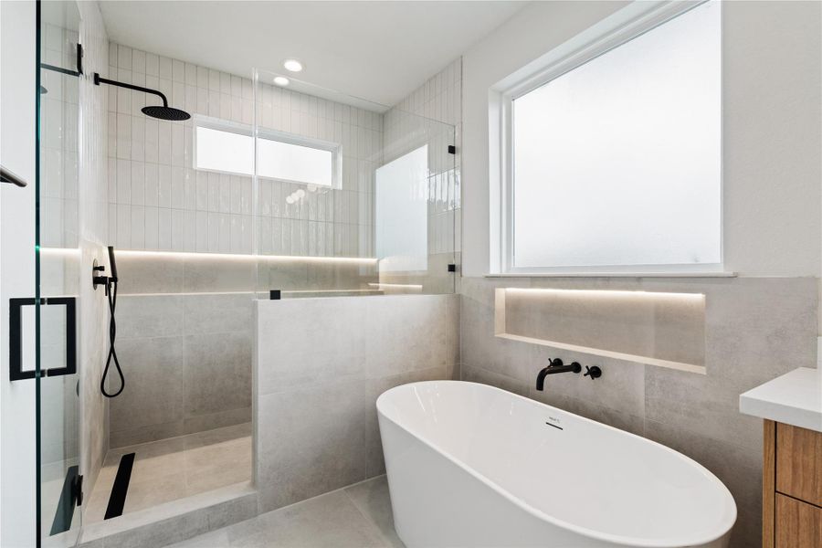 Beautiful walk-in shower and freestanding tub with modern tilework and sleek black fixtures.