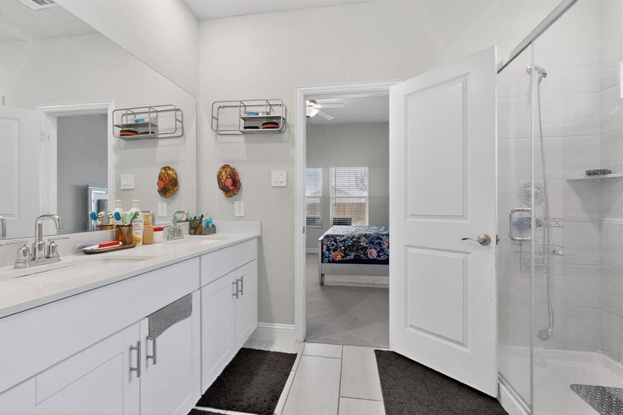 Full bathroom with connected bathroom, double vanity, light tile patterned flooring, and a shower stall Full bathroom with connected bathroom, double vanity, light tile patterned flooring, and a shower stall