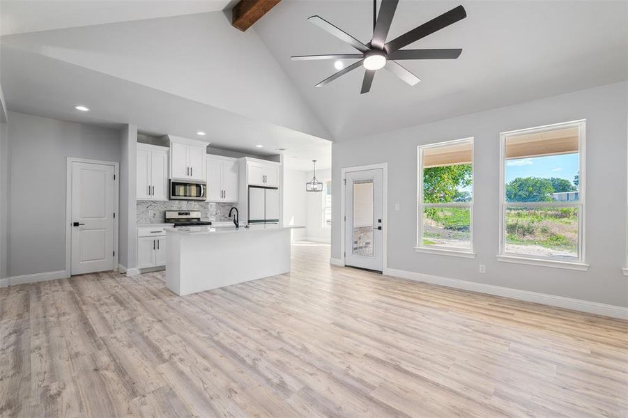 Unfurnished living room with beam ceiling, ceiling fan, light wood-style floors, recessed lighting, and high vaulted ceiling Unfurnished living room with beam ceiling, ceiling fan, light wood-style floors, recessed lighting, and high vaulted ceiling