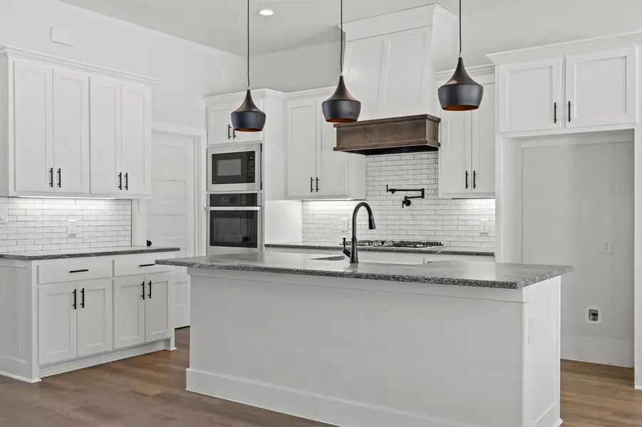Kitchen with dark stone counters, white cabinetry, dark wood-style floors, and stainless steel appliances
