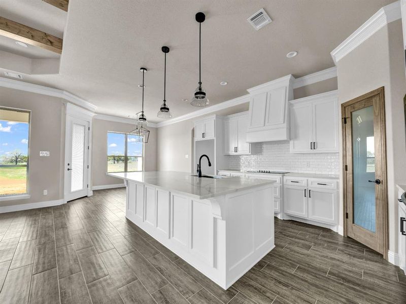 Kitchen featuring decorative backsplash, white cabinets, visible vents, a sink, and wood tiled floor Kitchen featuring decorative backsplash, white cabinets, visible vents, a sink, and wood tiled floor