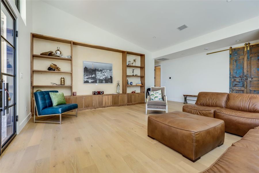 Living room featuring a barn door, light wood-style flooring, and lofted ceiling